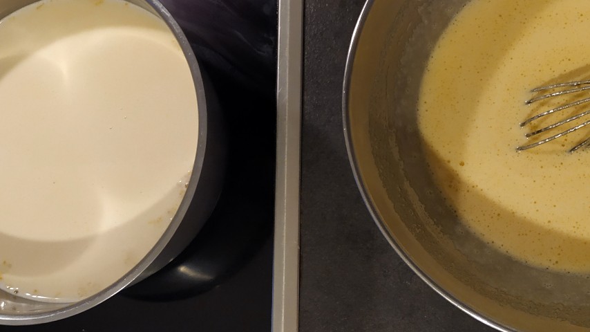 The milk heating up in a saucepan and the egg and sugar mixture beaten with a hand whisk