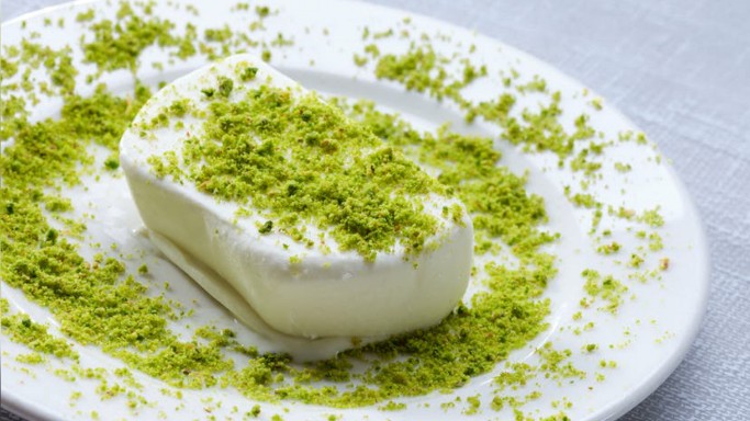 A slice of traditional dondurma sprinkled with pistachio on a white plate